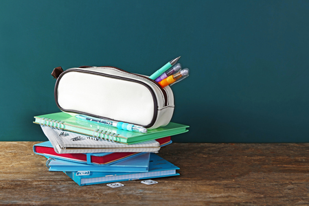 Pencil case with various stationery on old  wooden table, on blackboard backgroundの写真素材