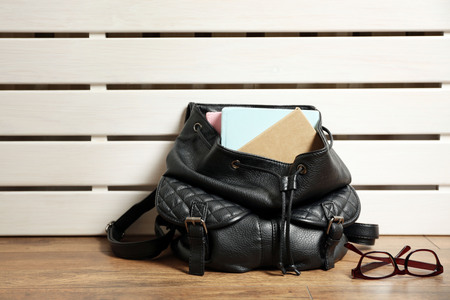 Fashion female backpack with books and glasses on wooden backgroundの写真素材