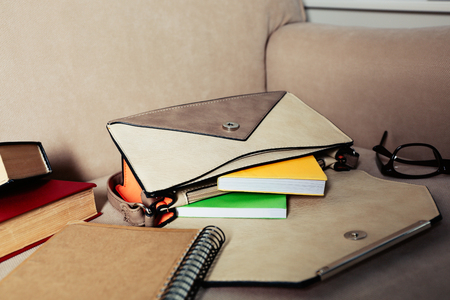 Fashion female handbag with books and glasses on a sofaの写真素材