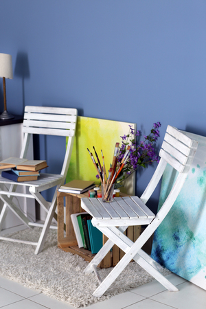 Room design with white furniture, bookcase, pictures, flowers over blue wallの写真素材
