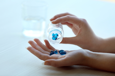Woman spills blue medical capsules  to her hand, close upの写真素材