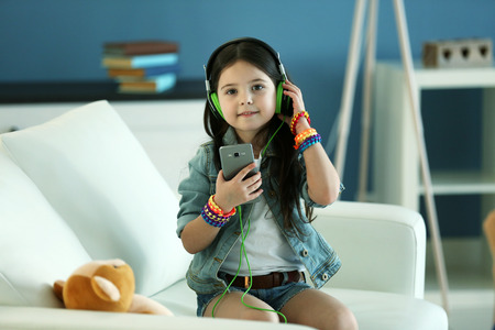 Cute little girl listening music and singing in the roomの写真素材