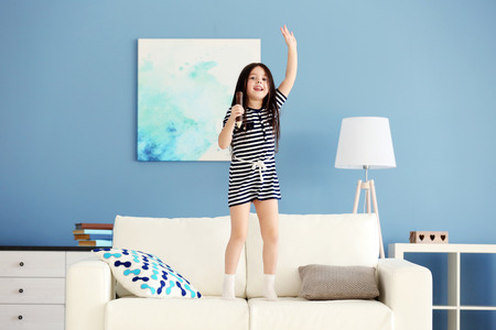 Cute little girl singing in a wooden pencil and has fun in the modern roomの写真素材