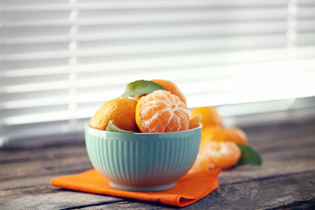 Tangerines in bowl on old wooden table, close upの写真素材