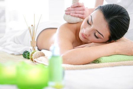 Spa concept. Someone do relaxing massage with herbal balls to beautiful woman, close upの写真素材