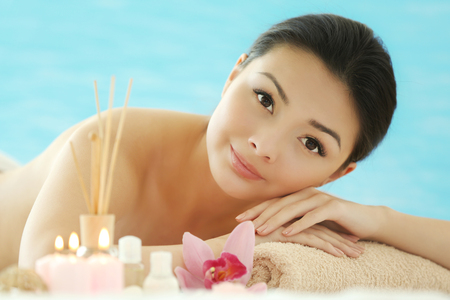 Spa concept. Young pretty woman relaxing on blue background, close upの写真素材
