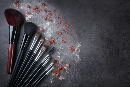 Makeup brushes and crushed rouges on gray backgroundの写真素材