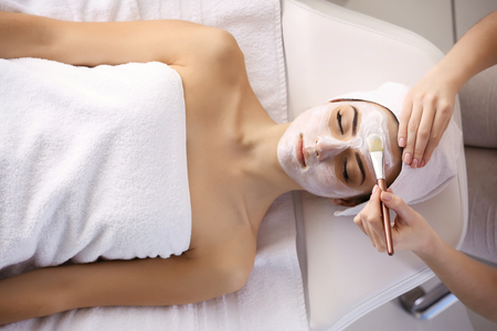 Spa concept. Young woman with facial mask in beauty salon, close upの写真素材