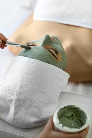 Spa concept. Young woman with nutrient facial mask in beauty salon, close upの写真素材