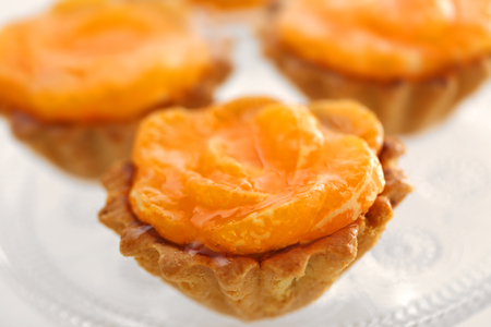 Sweet cakes with tangerines on plate, close upの写真素材
