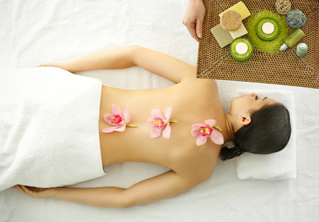 Spa concept. Woman relaxing with orchids on her back