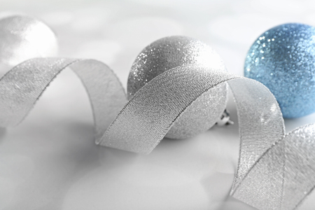 Silver curly ribbon with decorative baubles on shiny backgroundの写真素材