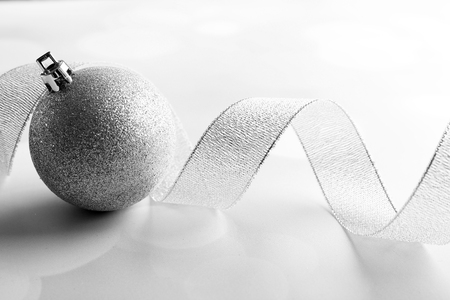 Silver curly ribbon with decorative baubles on shiny backgroundの写真素材