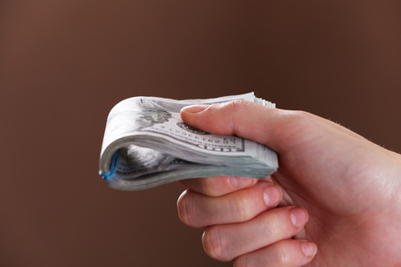 Hand holds money on brown background, close up