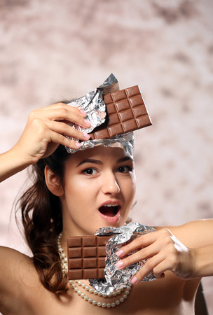 Portrait of beautiful young woman with chocolate on blurred background, close upの写真素材