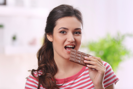Portrait of beautiful young brunette with chocolate in the room , close upの写真素材