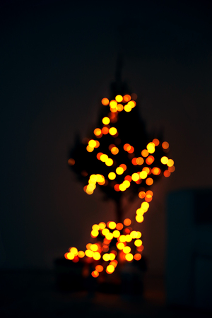 Christmas tree decorated with lights in the dark roomの写真素材