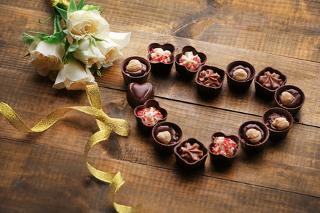 Set of chocolate candies forming heart on a wooden backgroundの写真素材