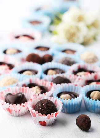 Set of chocolate candies with flowers on a light wooden background, close upの写真素材