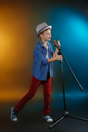 Little boy singing with microphone on a dark lighted backgroundの写真素材