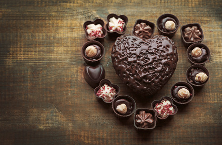 Set of chocolate candies forming heart on a wooden backgroundの写真素材