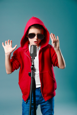 Little boy singing with microphone on a grey backgroundの写真素材