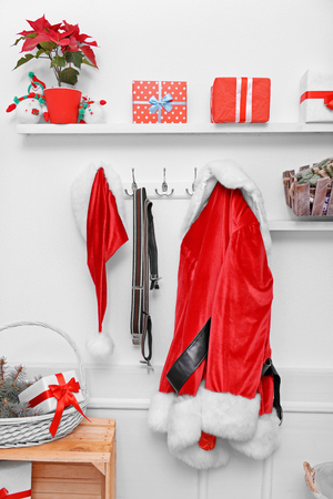 Santa costume hanging on white wall. Decorated Christmas room.の写真素材