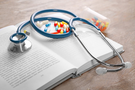 Stethoscope with pills and book, closeupの写真素材