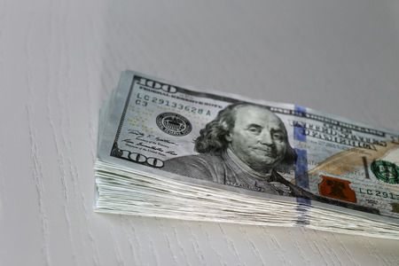 Stack of dollar banknotes on light wooden backgroundの写真素材