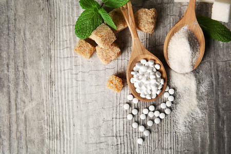Pile of brown sugar cubes and stevia  on grey wooden backgroundの写真素材