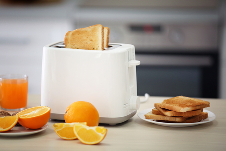 Toaster with dishes, sandwiches and oranges on a light kitchen tableの写真素材