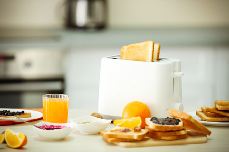 Toaster with dishes, sandwiches and oranges on a light kitchen tableの写真素材