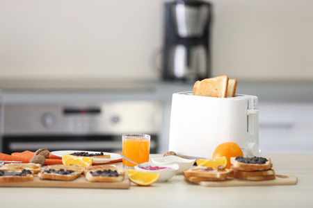 Toaster with dishes, sandwiches and oranges on a light kitchen tableの写真素材