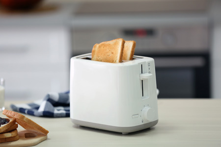 Toaster with dishes and sandwiches on a light kitchen table