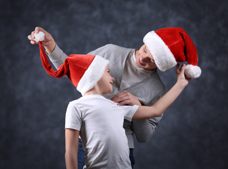 Brothers in Santa hats have fun on grey backgroundの写真素材