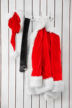 Santa jacket, hat and belt on a wooden white wallの写真素材