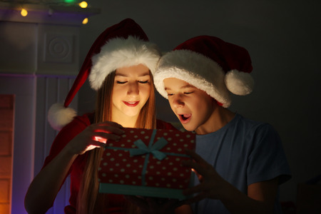 Happy sister and brother open gift box on the floor in decorated Christmas roomの写真素材