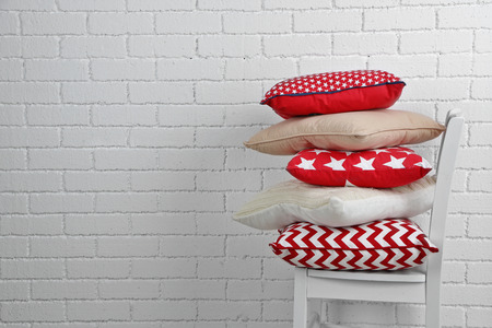 Colorful pillows on chair, on white bricks wall backgroundの写真素材