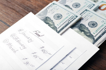 Distribution of money, financial planning, dollars in envelopes on wooden table background