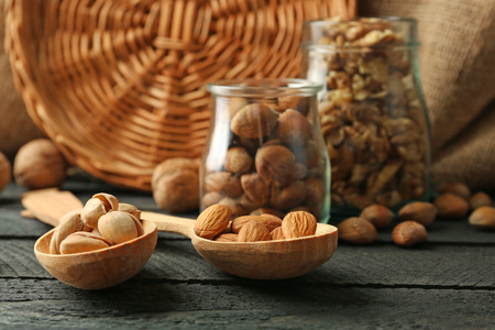 Mix of nuts in the glass jars and wooden spoon, on the table