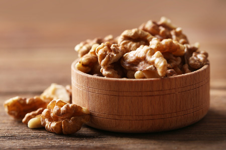 Walnut kernels in the wooden bowl on the table, close-upの写真素材
