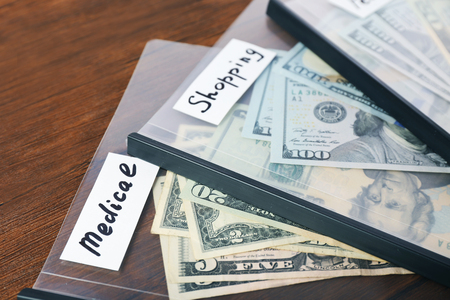 Distribution of money, financial planning, dollars in envelopes, on wooden table backgroundの写真素材
