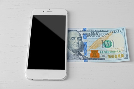 Smart phone and dollar banknote on light table. Telephone chargesの写真素材