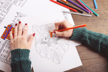 Female hand painting anti stress colouring with orange felt penの写真素材