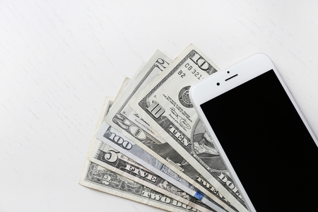 Smart phone on dollar banknotes over light table. Internet earning conceptの写真素材