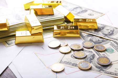 Gold bars with dollar banknotes and euro coins on paper backgroundの写真素材