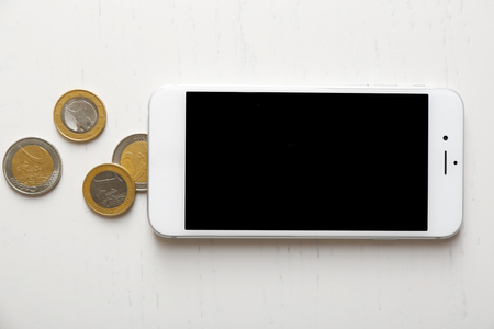 Smart phone and euro coins on light table. Telephone chargesの写真素材