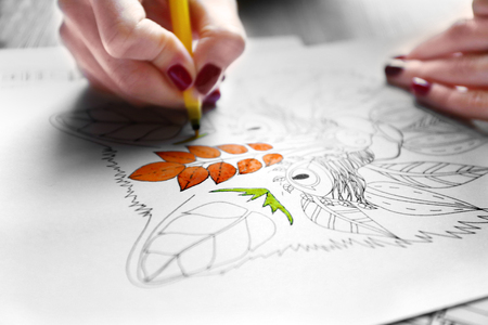 Female hand painting anti stress colouring with yellow felt pen