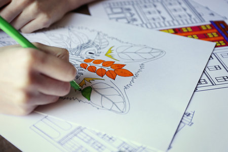Female hand painting anti stress colouring with green felt penの写真素材
