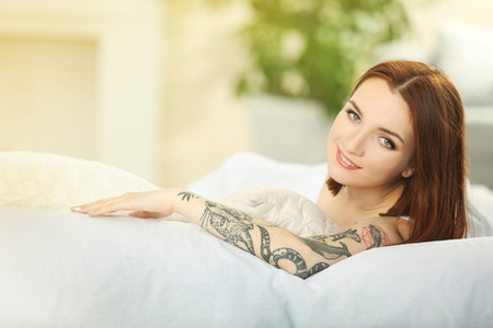 Attractive woman with tattoo lying on the bedの写真素材